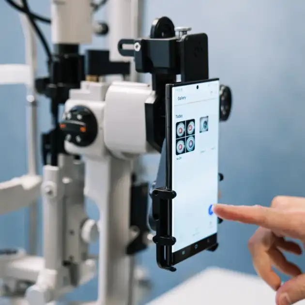 User selecting an eye photo from the MicroREC app on a smartphone attached to OptiREC to a slit lamp